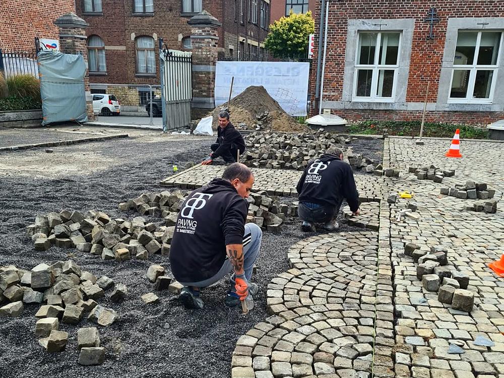 Paveurs de TBP Paving en sweat noir posant une mosaïque en éventail